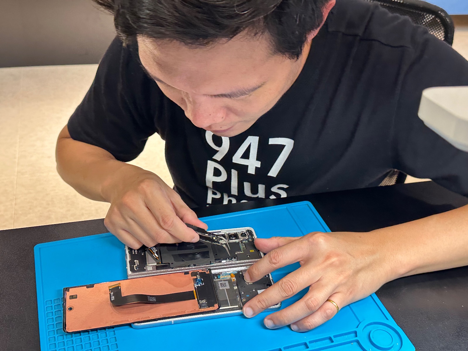 技師在工作台操作摺疊手機拆修